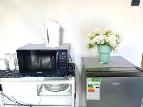 a microwave on top of a refrigerator with a vase of flowers at 63 Lodging Villa in Rustenburg
