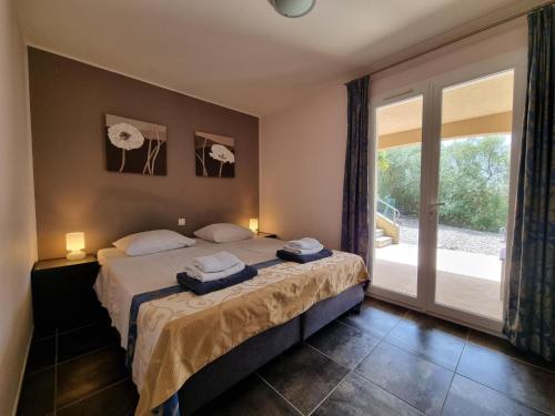sypialnia z 2 łóżkami i przesuwnymi szklanymi drzwiami w obiekcie Le Jardin des Olives w mieście Caunes-Minervois