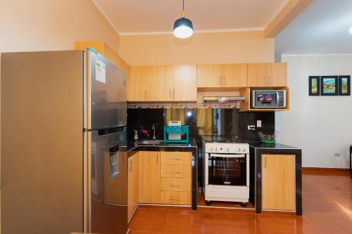 eine Küche mit einem Kühlschrank aus Edelstahl und Holzschränken in der Unterkunft Edificio Rojo Departamentos. in Tarapoto