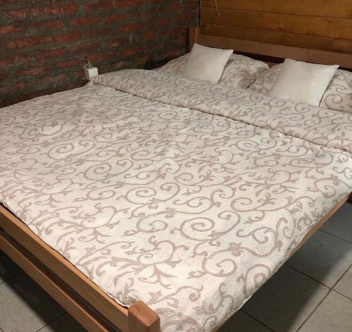 a bed with a comforter and pillows on it at Vila Ivona in Čačak