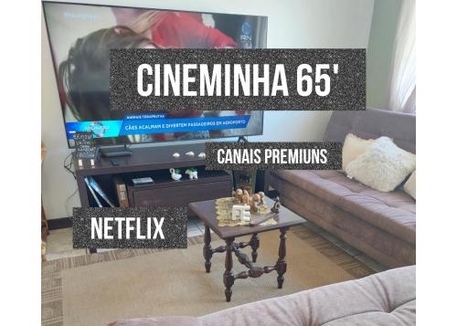 ein Wohnzimmer mit einem TV und einem Couchtisch in der Unterkunft Incrível Sacada à Beira Mar APTO 3Q in Tramandaí