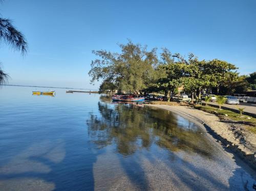 a body of water with trees and boats on the shore at Pousada Canto da Praia in São Pedro da Aldeia