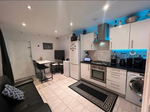 uma cozinha com armários brancos e uma mesa em Modern Appartment em Londres