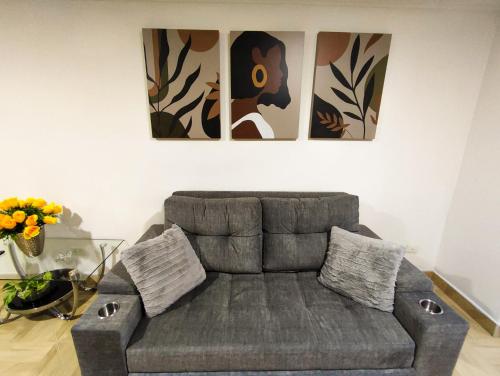 a grey couch in a living room with paintings on the wall at Apartamento en Laureles con Excelente Ubicación in Medellín