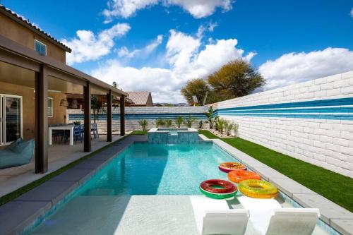 een zwembad met drie kleurrijke stoelen naast een huis bij Backyard Pool Oasis @ Tropicale Blue in Coachella