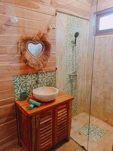 a bathroom with a sink and a heart shaped mirror at villa gilimakyah in Gili Air