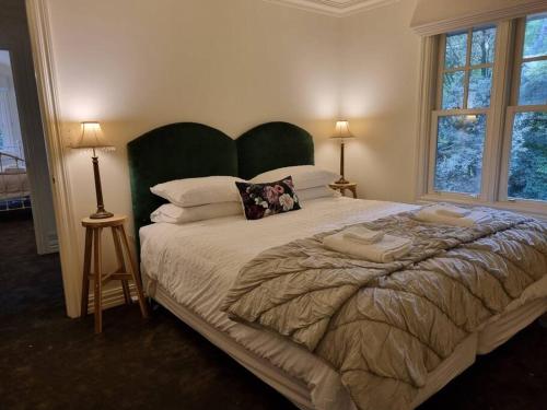 a bedroom with a large bed with a green headboard at Noonan House, 5 bedrooms. Hop & skip to town in Woodend