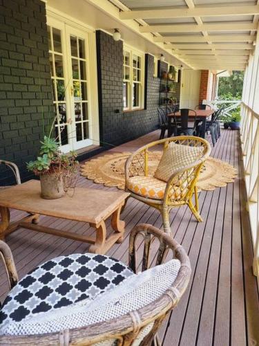 a porch with chairs and a table and tables at Noonan House, 5 bedrooms. Hop & skip to town in Woodend
