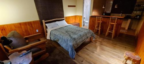 a small bedroom with a bed and a kitchen at Cantinho de Mauá in Visconde De Maua