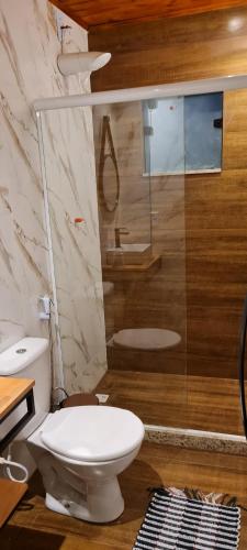 a bathroom with a toilet and a glass shower at Cantinho de Mauá in Visconde De Maua