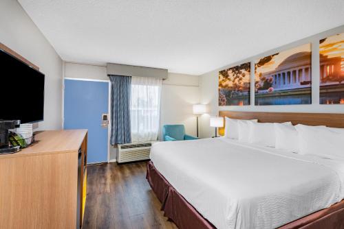 ein Hotelzimmer mit einem Bett und einem Flachbild-TV in der Unterkunft Days Inn by Wyndham Charlottesville/University Area in Charlottesville