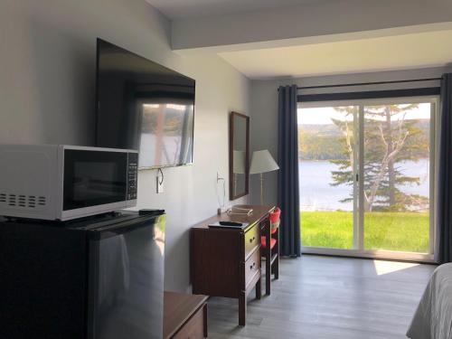 a living room with a television and a door with a window at Duck Cove Inn in Margaree Harbour