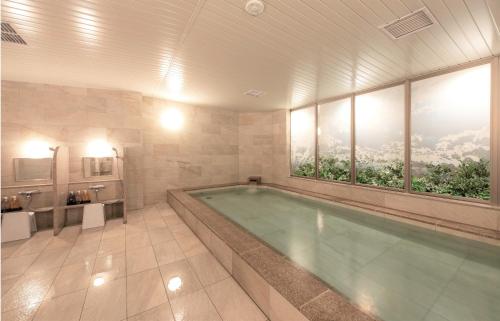 un ampio bagno con piscina con ampia finestra di Hotel GrandBach Sendai a Sendai