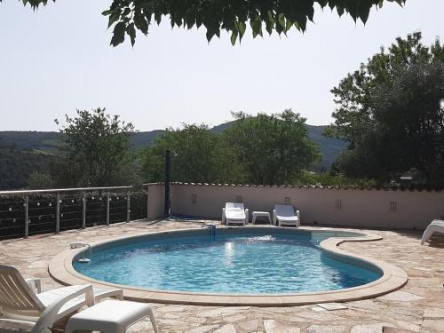 a swimming pool with two chairs at Sunny Roquebrun Getaway in Roquebrun