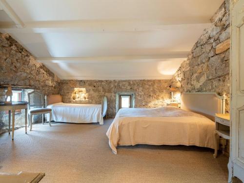 une chambre avec deux lits et un mur en pierre dans l'établissement Holiday Home in Ardèche with Private Pool, à Labeaume