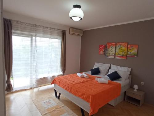 a bedroom with a bed with an orange blanket and a window at Apartman Šimun in Rijeka