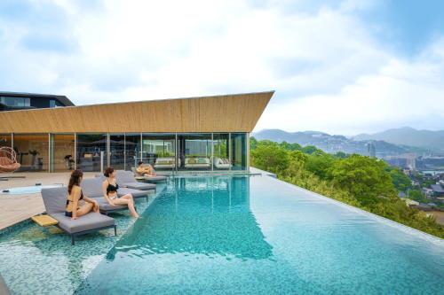a swimming pool with two women sitting on the edge of a building at Garden Terrace Nagasaki Hotels & Resorts in Nagasaki
