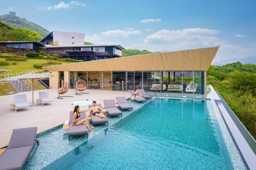 a pool with people sitting on chairs next to a building at Garden Terrace Nagasaki Hotels & Resorts in Nagasaki