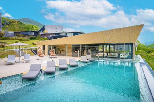 a swimming pool with lounge chairs and a building at Garden Terrace Nagasaki Hotels & Resorts in Nagasaki