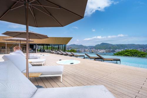 a deck with a bunch of chairs and umbrellas at Garden Terrace Nagasaki Hotels & Resorts in Nagasaki