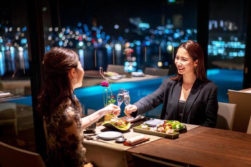 two women sitting at a table in a restaurant eating food at Garden Terrace Nagasaki Hotels & Resorts in Nagasaki