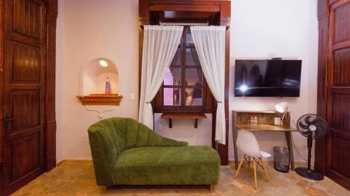 a living room with a green chair and a television at Casa Eva Hotel Boutique & Spa in Cholula