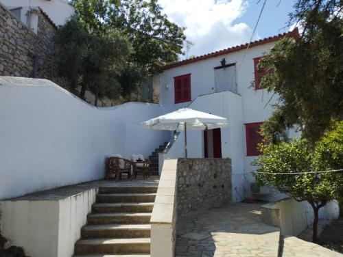 een wit huis met een trap en een paraplu bij Othon's Guest House in Hydra