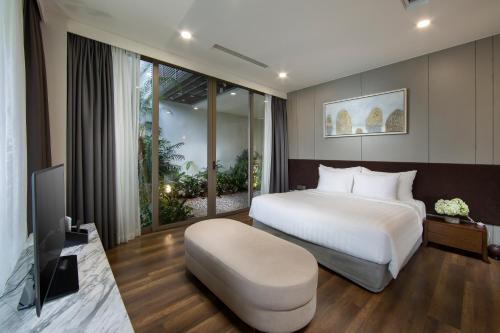 a bedroom with a white bed and a television at Flamingo Resort Dai Lai in Ngọc Quang