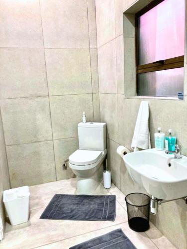 a bathroom with a white toilet and a sink at 63 Lodging Villa in Rustenburg