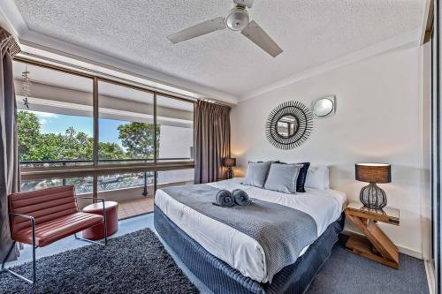 a bedroom with a bed and a chair and a window at Shelby On Eshelby in Airlie Beach