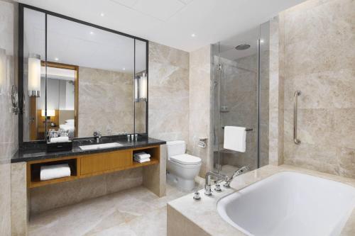a bathroom with a tub and a toilet and a sink at Courtyard by Marriott Zhengzhou East in Zhengzhou