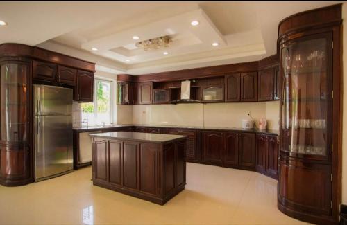 uma grande cozinha com armários de madeira e um frigorífico em Promotion summer vacation, Ocean Villa Nha Trang 600m2 with 7 Bedrooms, Karaoke, BBQ em Nha Trang