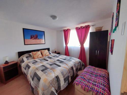 a bedroom with a bed and a window with red curtains at Dunas de tulor in San Pedro de Atacama