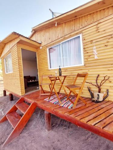 a cabin with two chairs and a table on a wooden deck at Dunas de tulor in San Pedro de Atacama