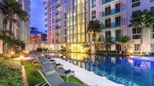 a swimming pool with lounge chairs in front of a building at City Center Residence Kim in Pattaya