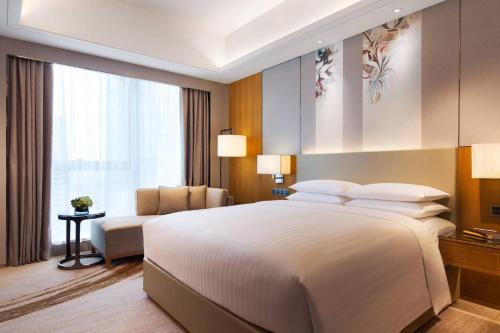 - une chambre avec un grand lit blanc et un canapé dans l'établissement Courtyard by Marriott Zhengzhou East, à Zhengzhou