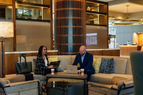 a man and a woman sitting on a couch with a laptop at Crowne Plaza Atlanta Perimeter at Ravinia by IHG in Atlanta