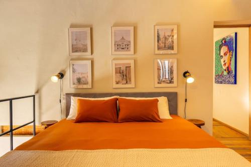 een slaapkamer met een oranje bed met foto's aan de muur bij Magnificient downtown apartment in Mexico-Stad