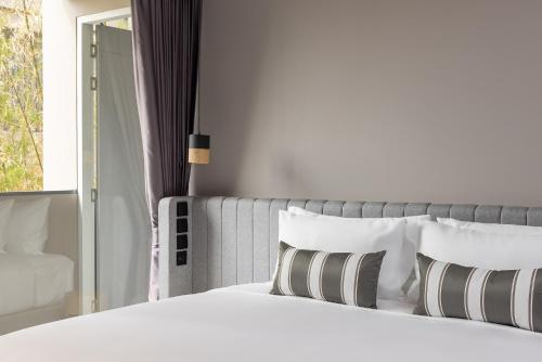 a bedroom with a white bed with pillows and a window at Travelodge Nimman in Chiang Mai