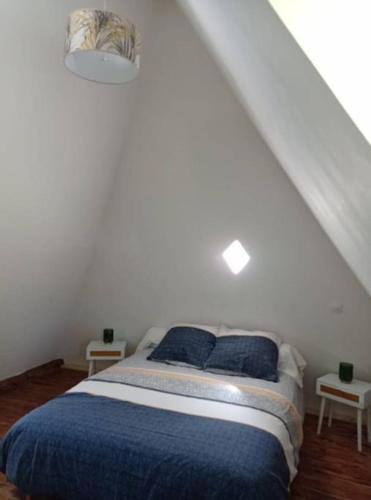 - une chambre blanche avec un lit et des oreillers bleus dans l'établissement La Pommeraie, à La Poterie-Mathieu