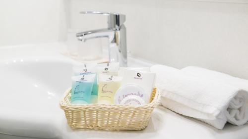 un lavabo con una cesta de cepillos de dientes y toallas en Hotel Eden Garda, en Garda