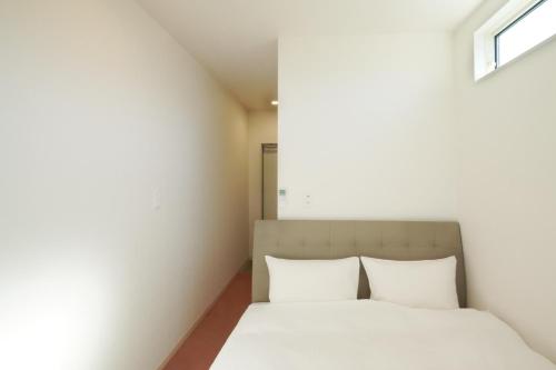 a bedroom with a bed with white sheets and a window at Hotel Cradle Cabin Tateyama in Tateyama