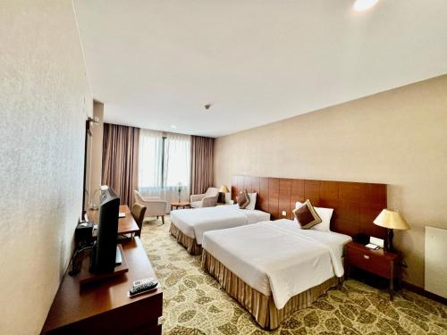 a hotel room with two beds and a television at AURORA Hotel Plaza in Bien Hoa