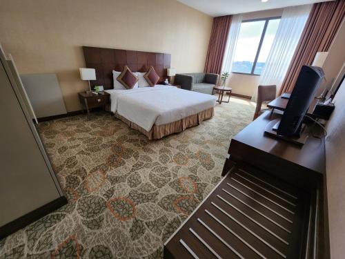a hotel room with a bed and a flat screen tv at AURORA Hotel Plaza in Bien Hoa