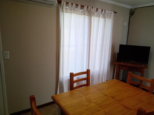 ein Esszimmer mit einem Holztisch und einem Fenster in der Unterkunft El refugio in San Antonio de Areco