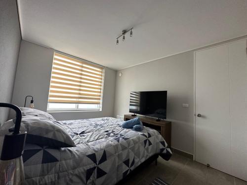 a bedroom with a bed and a flat screen tv at Hermoso departamento full equipado centro de Temuco in Temuco