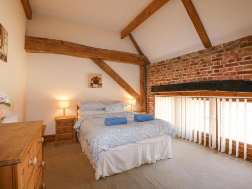 a bedroom with a bed and a brick wall at Hadleigh Farm Barn in Gayton