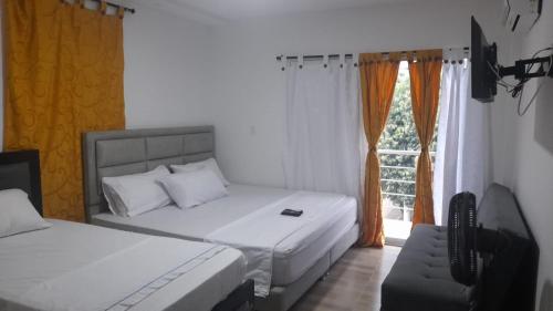 1 dormitorio con 2 camas, TV y ventana en Casa Hospedaje Sandra en Aguachica