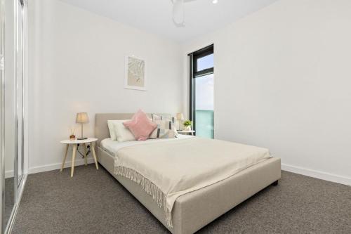 a white bedroom with a bed and a window at Ambrosia - East End Hillside Haven in Adelaide