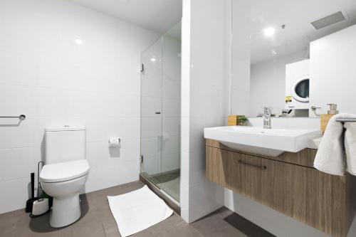 een witte badkamer met een toilet en een wastafel bij Isaac - The Cityscape View Apartment in Adelaide